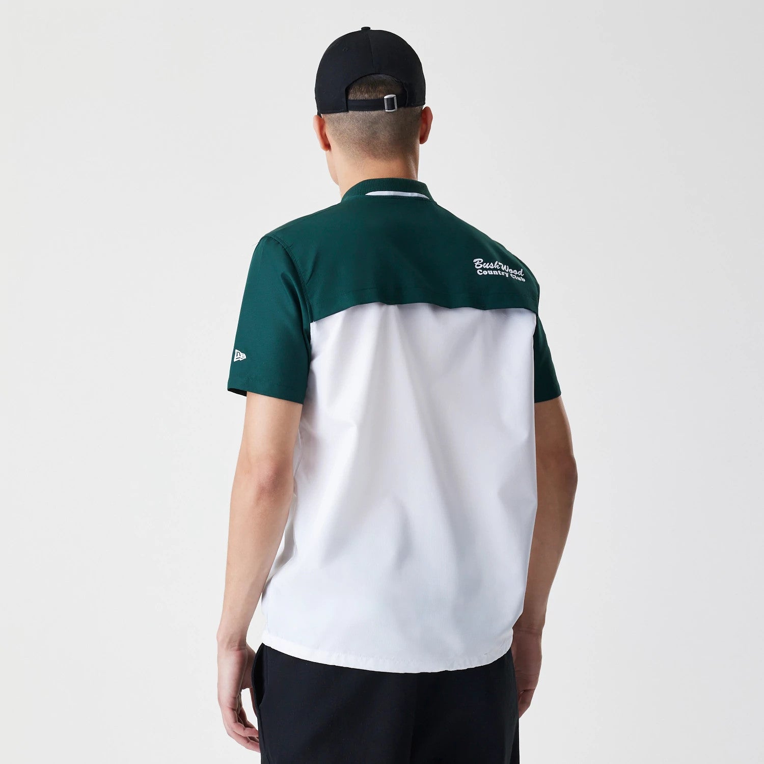 New Era Caddyshack BushWood White 1/4 Zip Polo T-Shirt, rear view showing a contrasting dark green upper and white lower section, with an embroidered logo on the right shoulder and a small embroidered logo on the left sleeve.