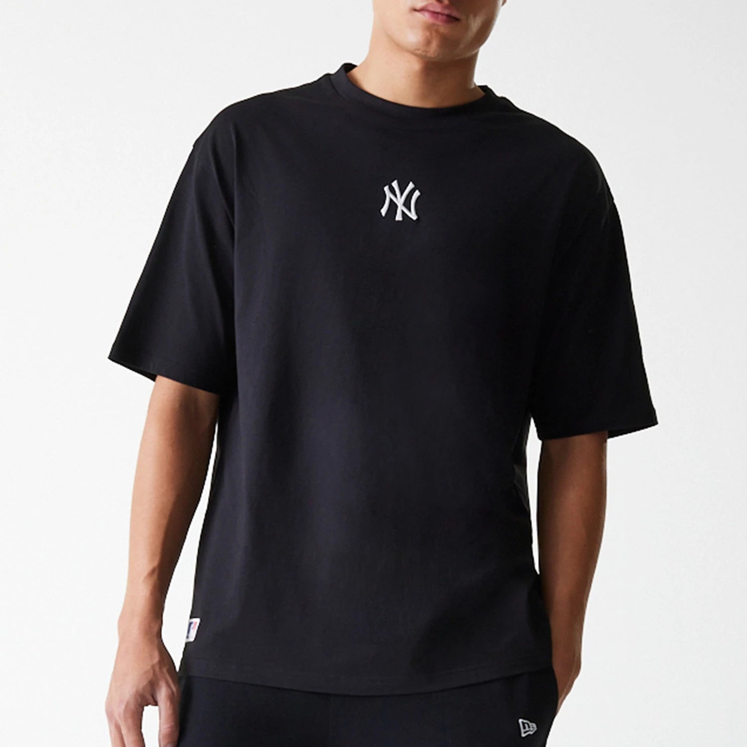 New Era New York Yankees MLB League Essential Black Oversized T-Shirt, front view showing the black T-shirt with a white embroidered New York Yankees logo centred on the chest below the round neckline.