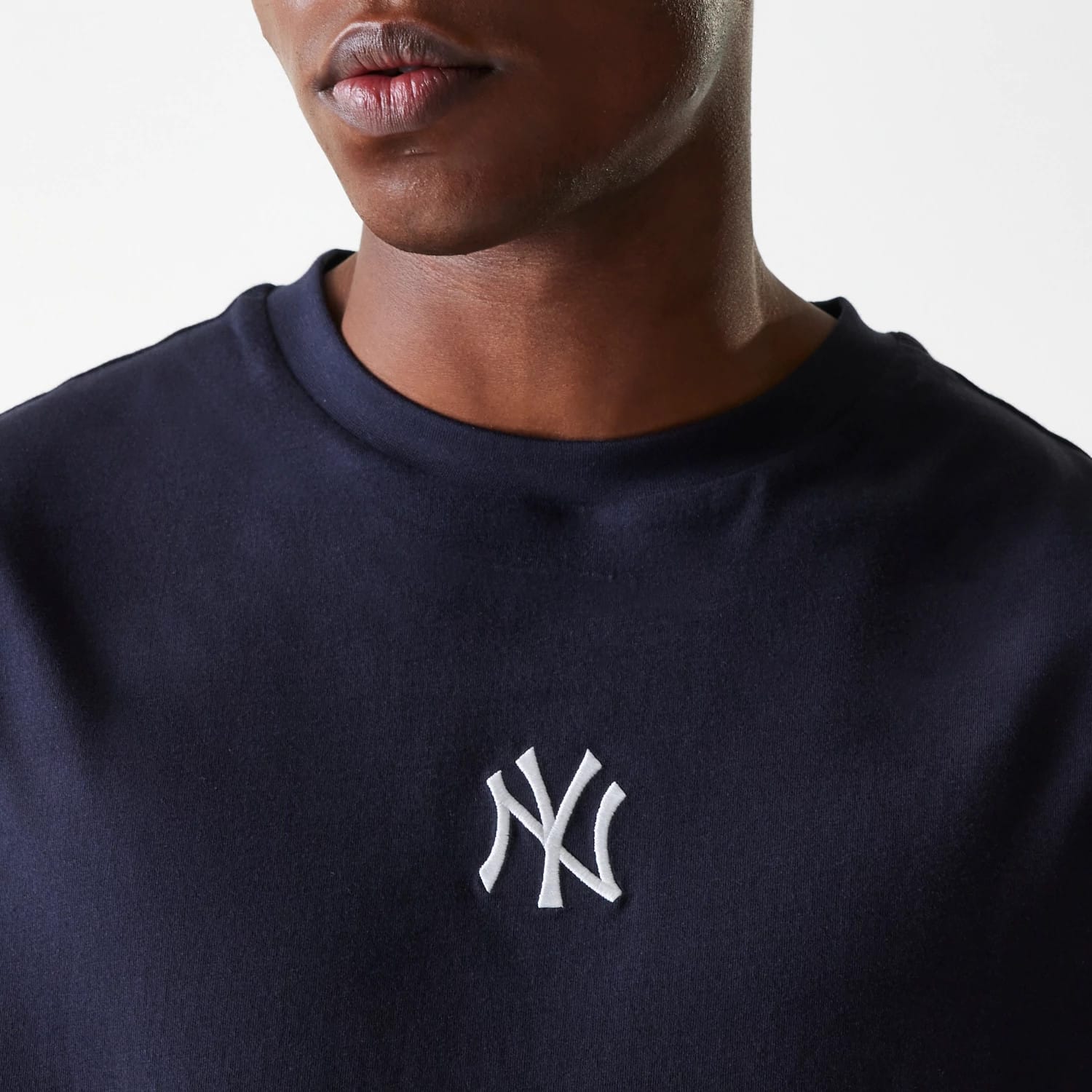 New Era New York Yankees MLB League Essential Navy Oversized T-Shirt, front view showing the raised New York Yankees logo embroidered in white on the chest of the dark navy fabric.