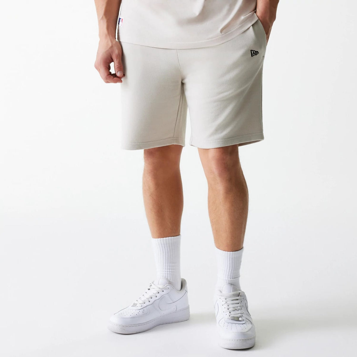 New Era New York Yankees MLB League Essential French Terry Cream Shorts, front view showing cream shorts with a raised black New Era logo on the left side and a small tag near the right pocket.