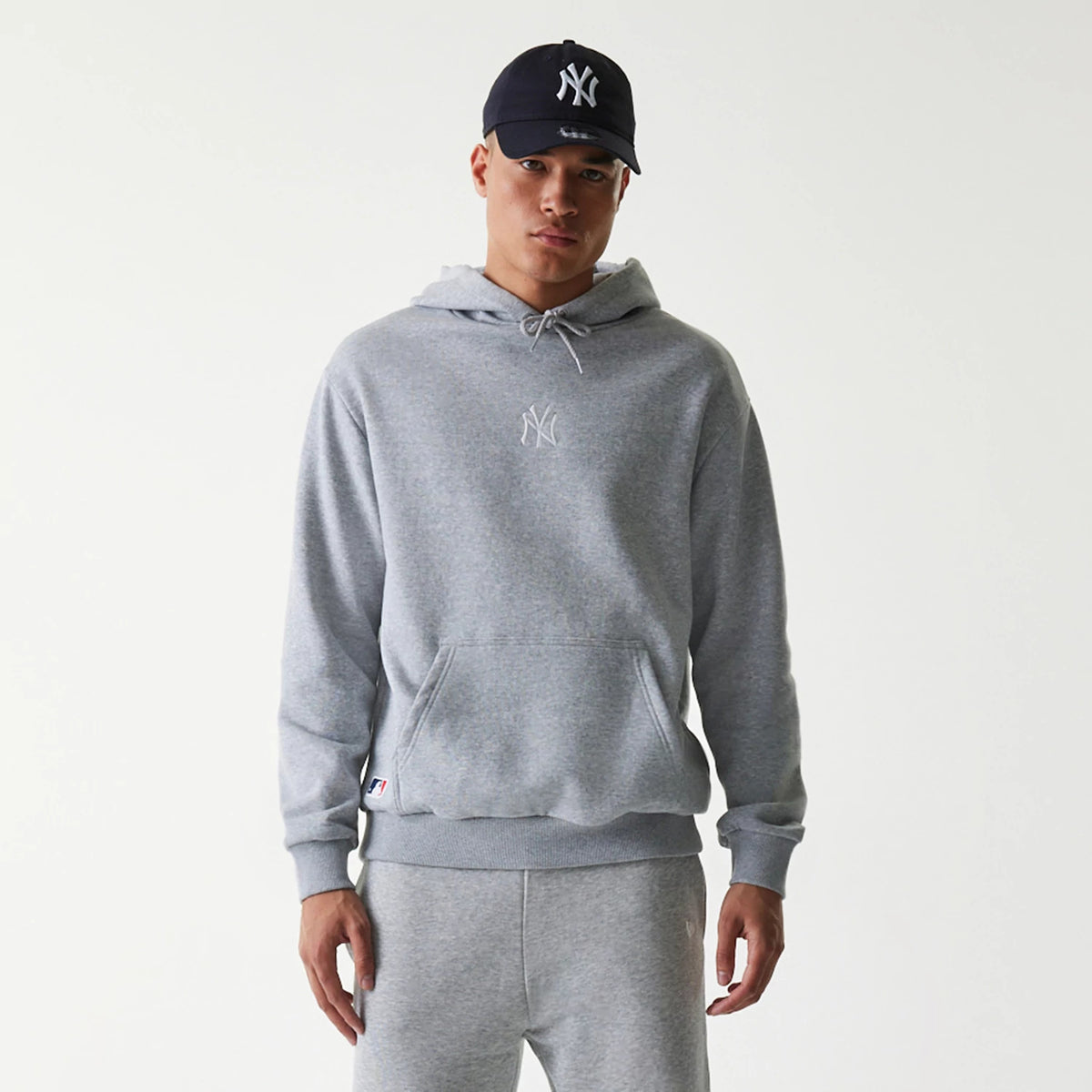 New Era New York Yankees MLB League Essential Grey Oversized Pullover Hoodie, front view showing the relaxed fit grey hoodie with a white raised New York Yankees logo centred on the chest and a drawstring hood.