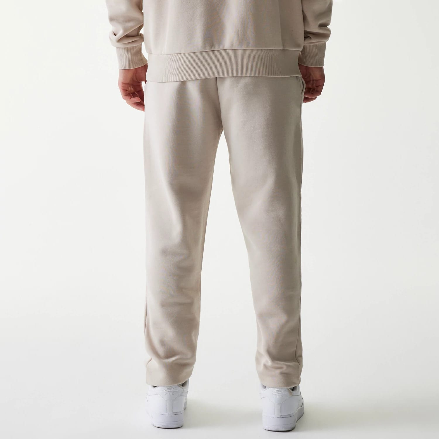 New Era New York Yankees MLB League Essential Cream Joggers, rear view on a model showing the relaxed fit with elasticated waistband and cuffs, paired with a matching cream sweatshirt and white trainers.