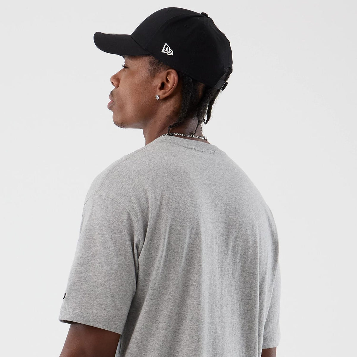 New Era LA Kings NHL Sport Classic Grey T-Shirt, on-model rear view highlighting the plain grey back with a small black debossed logo on the left sleeve, paired with a black cap featuring a raised logo on the side.