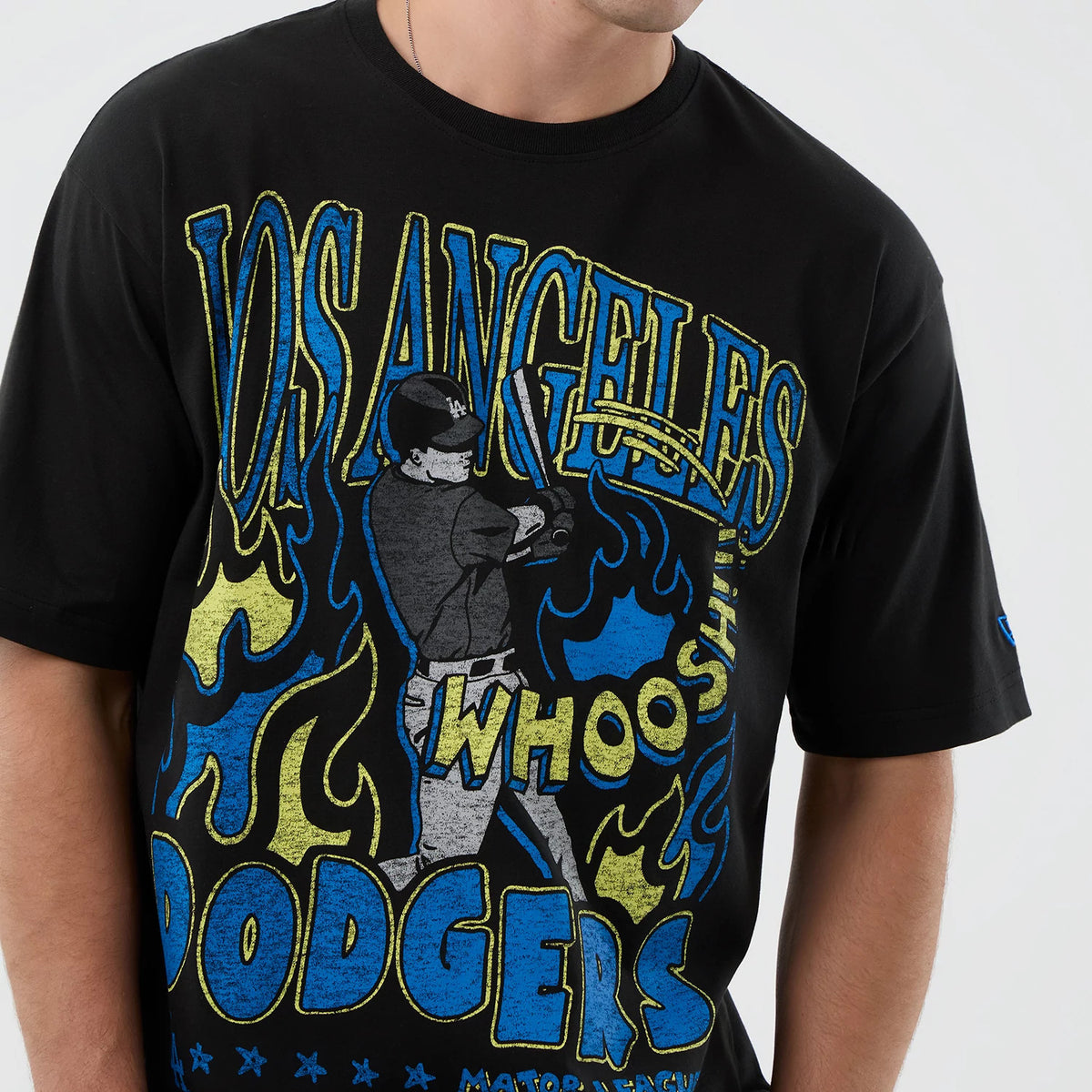 New Era LA Dodgers MLB Player Life Graphic Black T-Shirt, front view showing a large colourful graphic of a baseball player with Los Angeles text above, yellow and blue flames around, and a small debossed New Era logo on the left sleeve.
