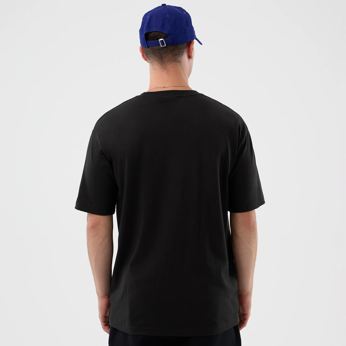 New Era LA Dodgers MLB Player Life Graphic Black T-Shirt, rear view showing the plain black back of the T-shirt worn by a model with a blue cap featuring eyelets and an adjustable strap closure.