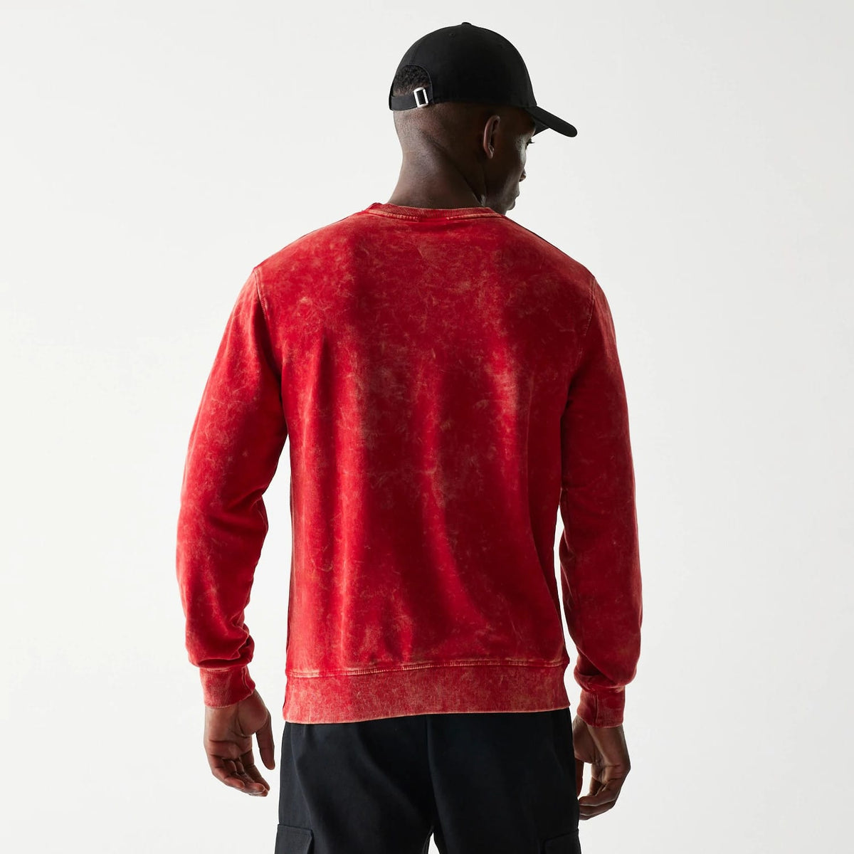New Era Kansas City Chiefs NFL Throwback Red Crew Neck Sweater, back view on a model wearing a black cap, showing distressed red fabric texture and a loose fit over the shoulders with ribbed cuffs and hem.