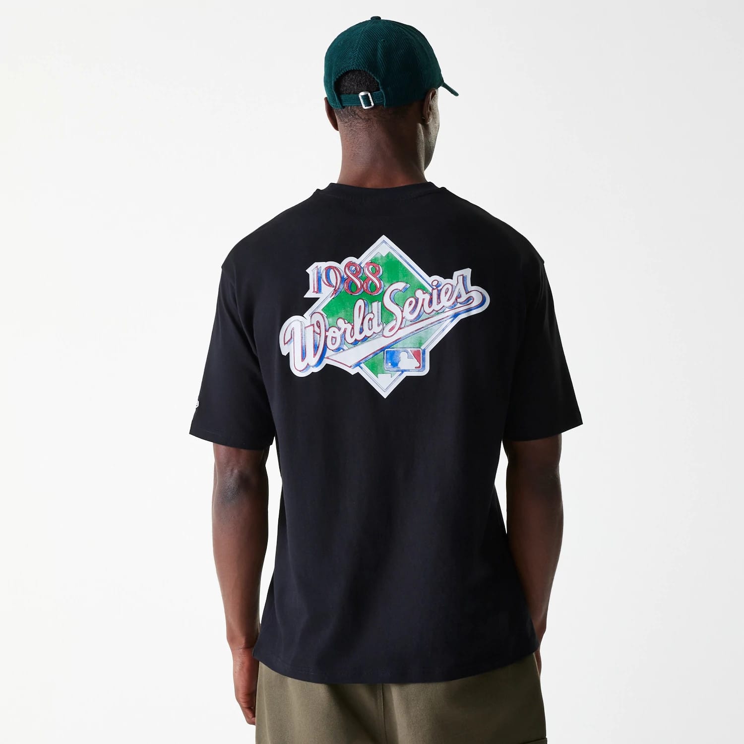 New Era LA Dodgers MLB World Series Black Oversized T-Shirt, rear view showing a large colourful 1988 World Series graphic centred on the back, a plain design extending across the black fabric, worn by a model in a green cap.