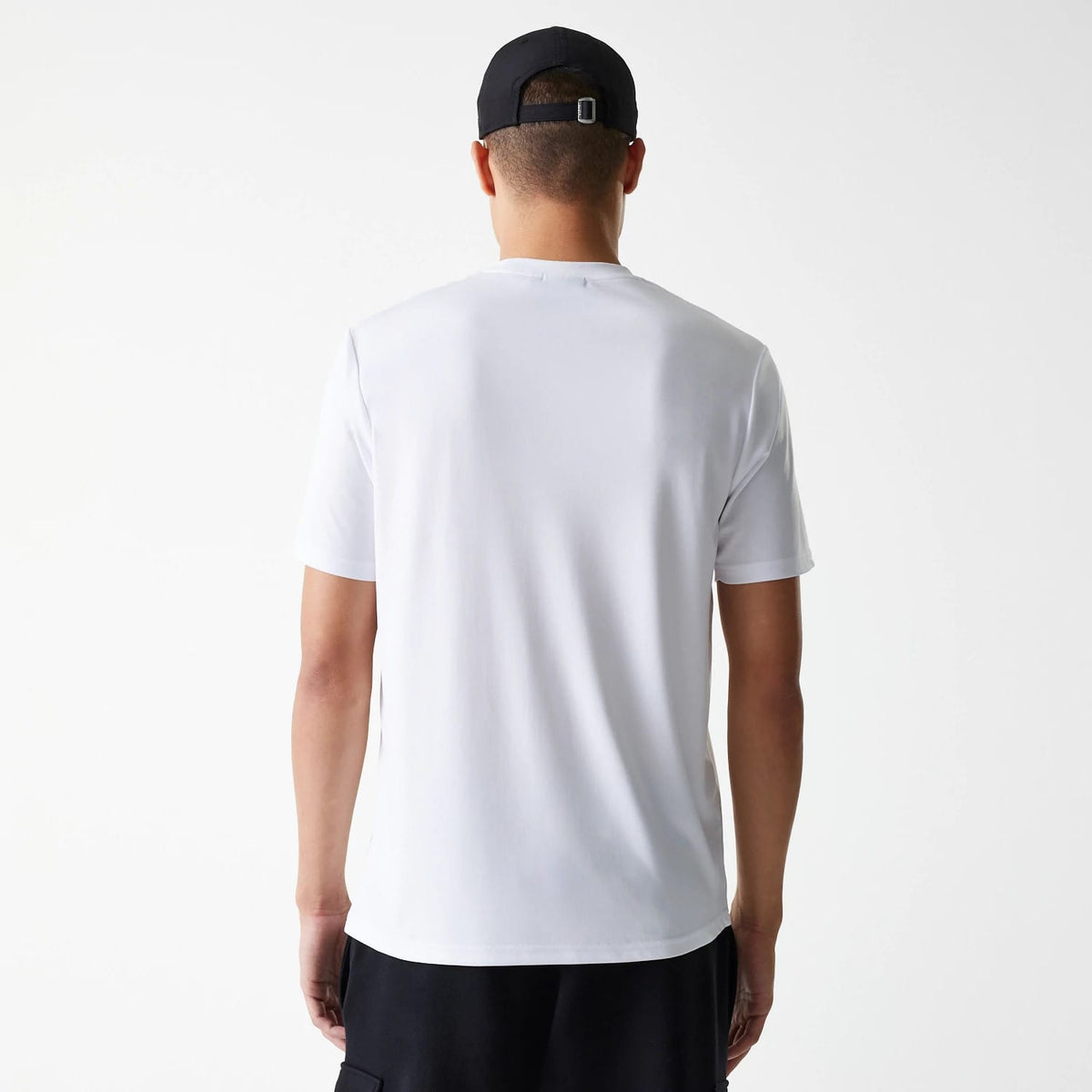 New Era Chicago Bulls NBA Essentials White T-Shirt, rear view showing a plain white back with short sleeves, worn by a person also wearing a black cap with a debossed logo positioned above the adjustable strap.