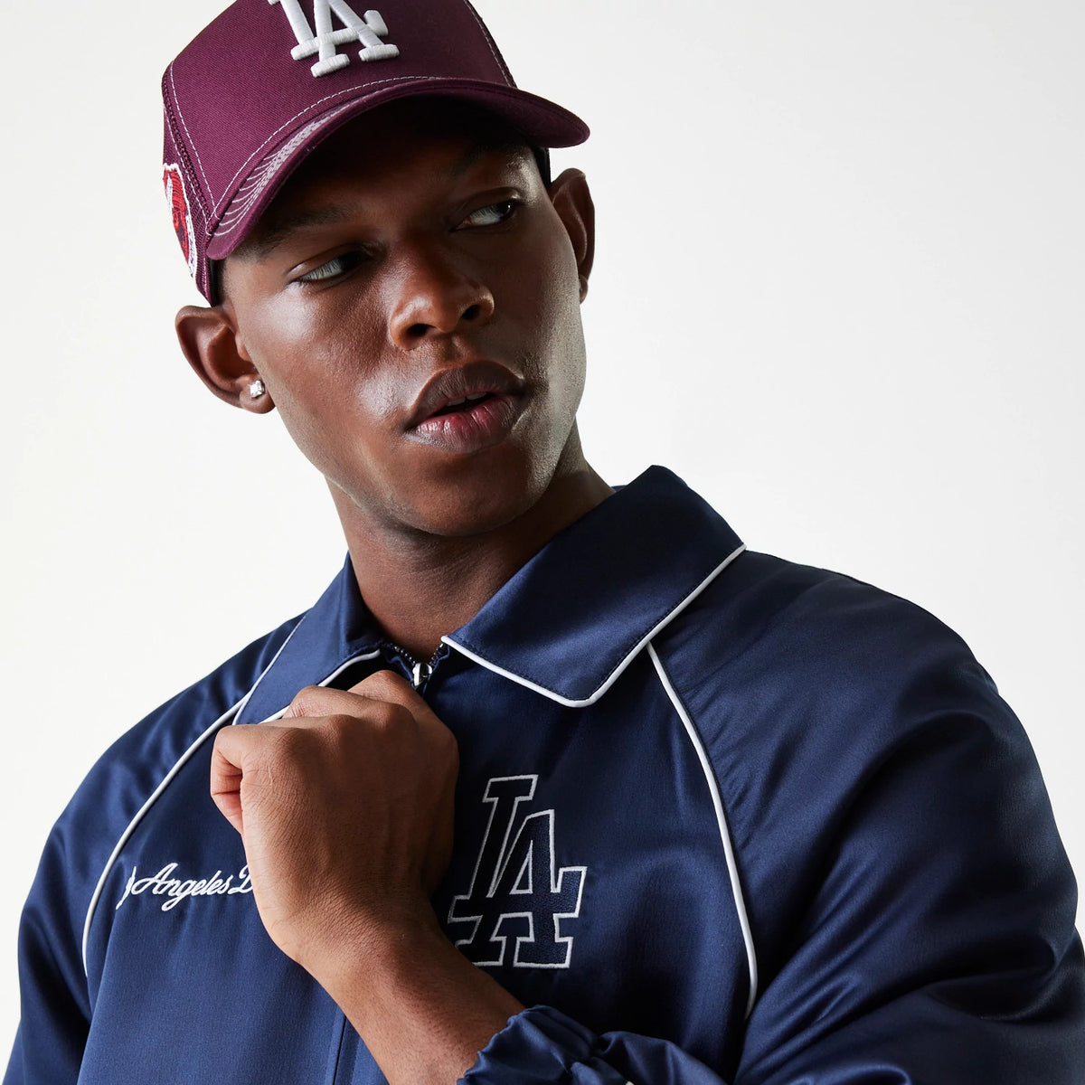 New Era LA Dodgers MLB Navy Club Jacket, on-model view showing the navy jacket with white piping and an embroidered LA logo on the left chest, paired with a maroon cap featuring a raised LA logo on the front.