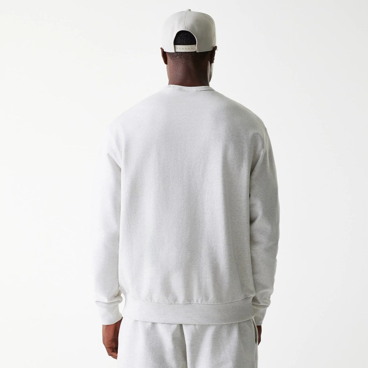 New Era LA Dodgers MLB Heritage Pastel Grey Oversized Crew Neck Sweater, rear view on a model wearing matching shorts and a backwards cap, showing the relaxed fit and ribbed hem and cuffs of the light grey design.