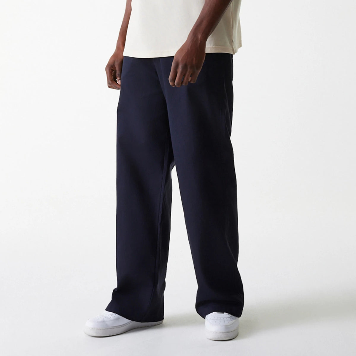 New Era LA Dodgers MLB Navy Chino Trousers, front view on a model paired with a light-coloured T-shirt and white trainers, showing the wide-leg fit and straight hemline of the navy trousers.