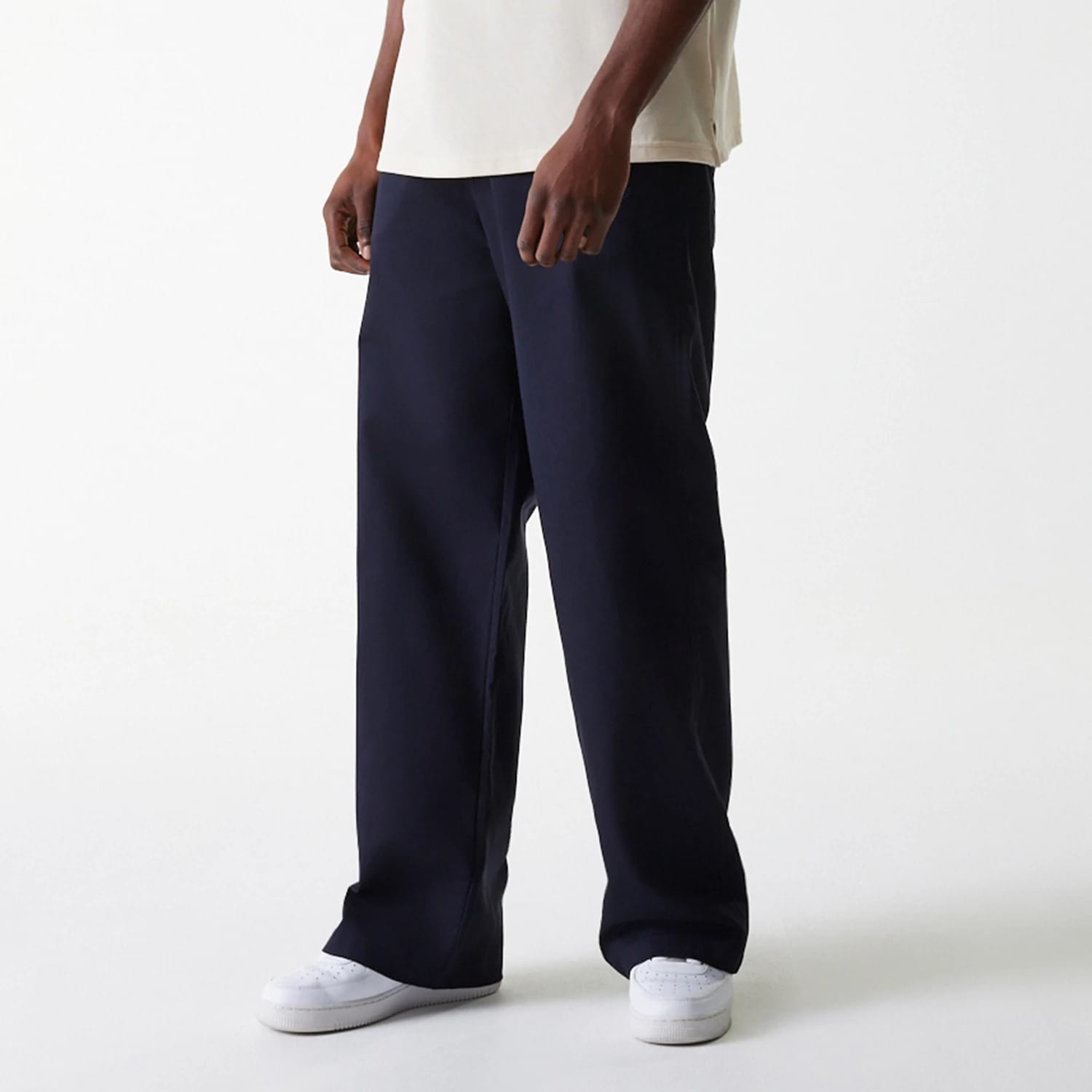 New Era LA Dodgers MLB Navy Chino Trousers, front view on a model paired with a light-coloured T-shirt and white trainers, showing the wide-leg fit and straight hemline of the navy trousers.