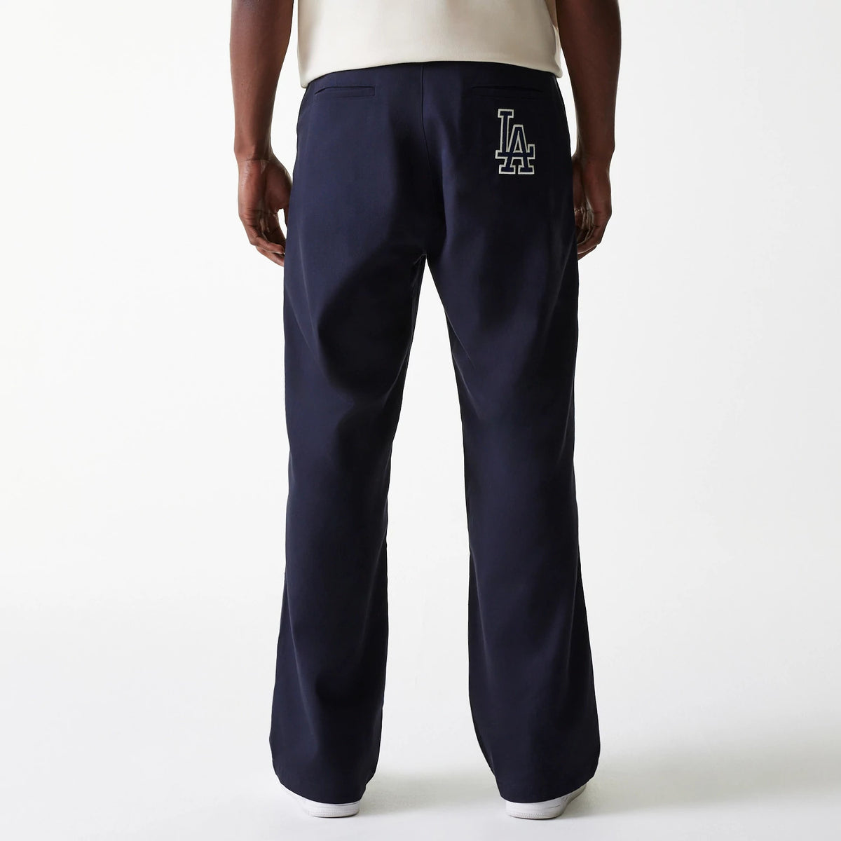 New Era LA Dodgers MLB Navy Chino Trousers, rear view on a model showing the white LA logo embroidered on the upper right pocket, with a straight-leg design and a plain back pocket on the left side.