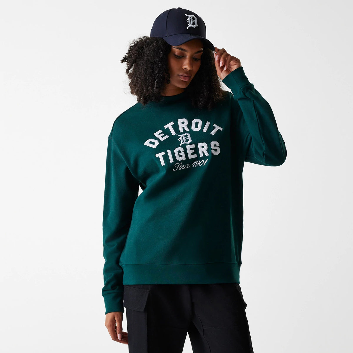 New Era Detroit Tigers MLB Heritage Dark Green Oversized Crew Neck Sweater, on a model wearing a navy cap, showing the white Detroit Tigers lettering and logo embroidered across the chest above Since 1901 text.