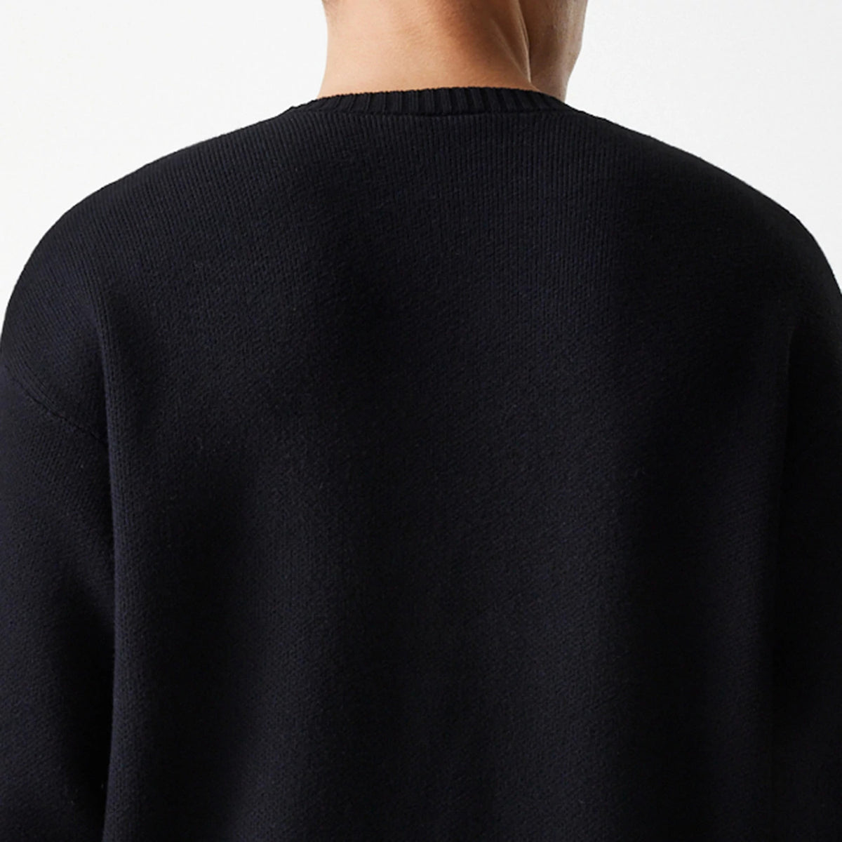 New Era Chicago Bulls NBA Knit Black Oversized Knit Sweater, rear view on a model wearing the sweater, featuring a ribbed crew neck and relaxed fit showcasing the knit texture of the black fabric.