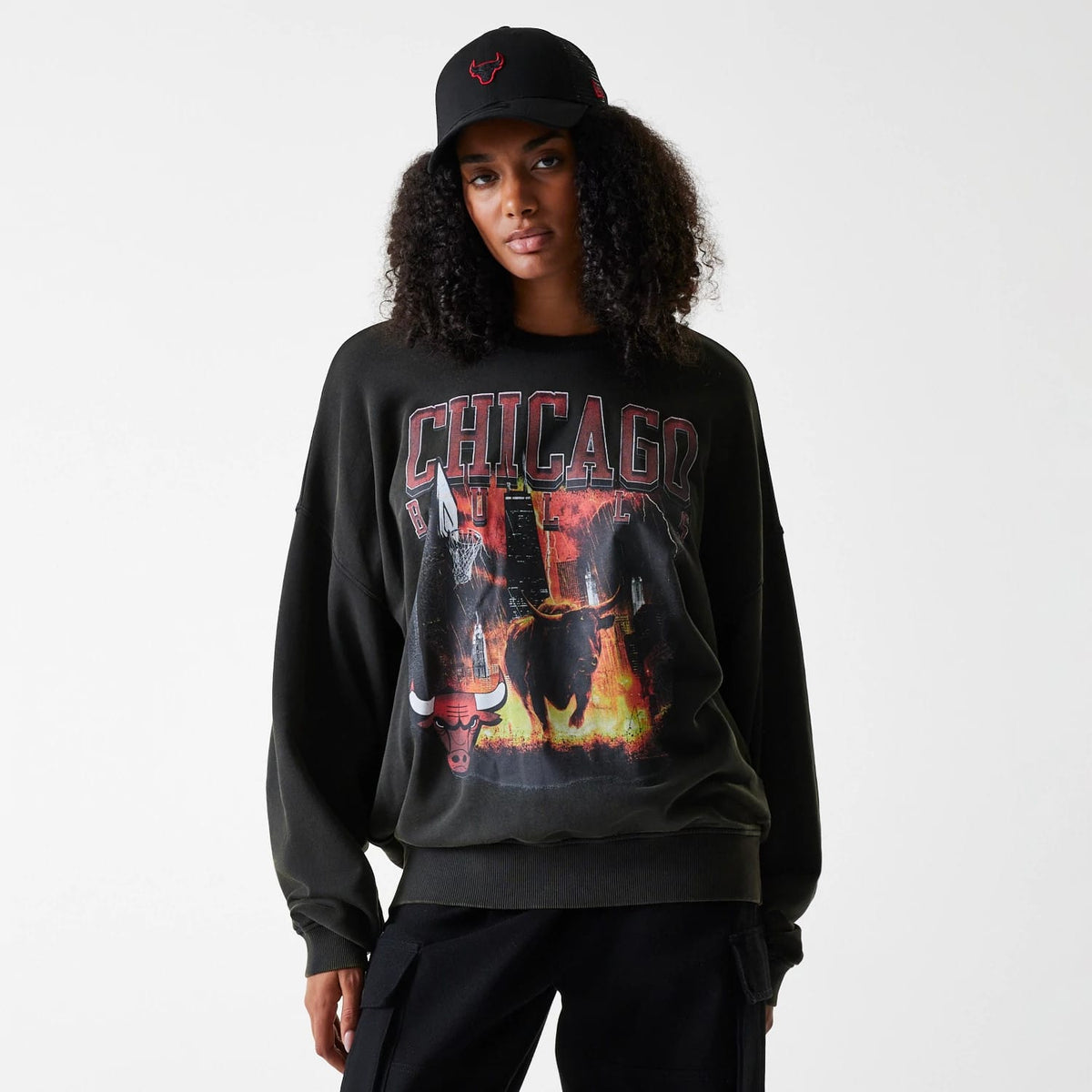 New Era Chicago Bulls NBA Washed Graphic Grey Oversized Crew Neck Sweater, front view on a model with a black cap, showing the bold Chicago lettering and dynamic Chicago Bulls graphic print across the chest.