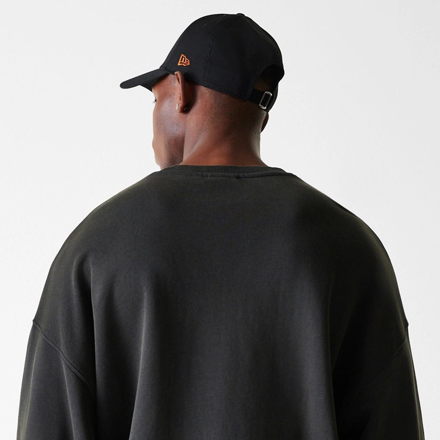 New Era Chicago Bulls NBA Washed Graphic Grey Oversized Crew Neck Sweater, rear view on a model with a black cap featuring an orange New Era flag logo on the left side, highlighting the relaxed fit and dropped shoulders.