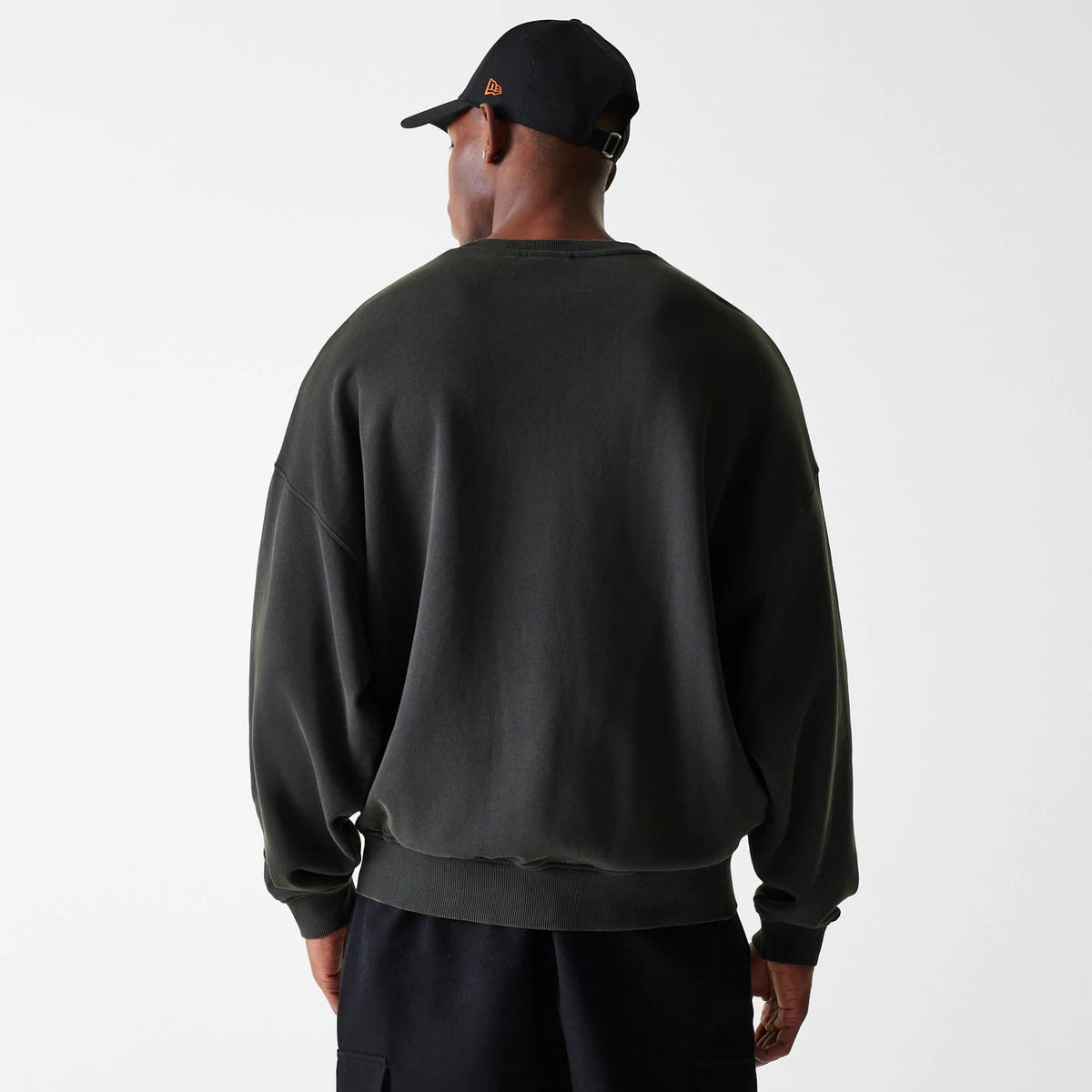 New Era Chicago Bulls NBA Washed Graphic Grey Oversized Crew Neck Sweater, back view on a model wearing a black cap with an orange New Era flag logo on the left side, highlighting the relaxed fit and ribbed hem.