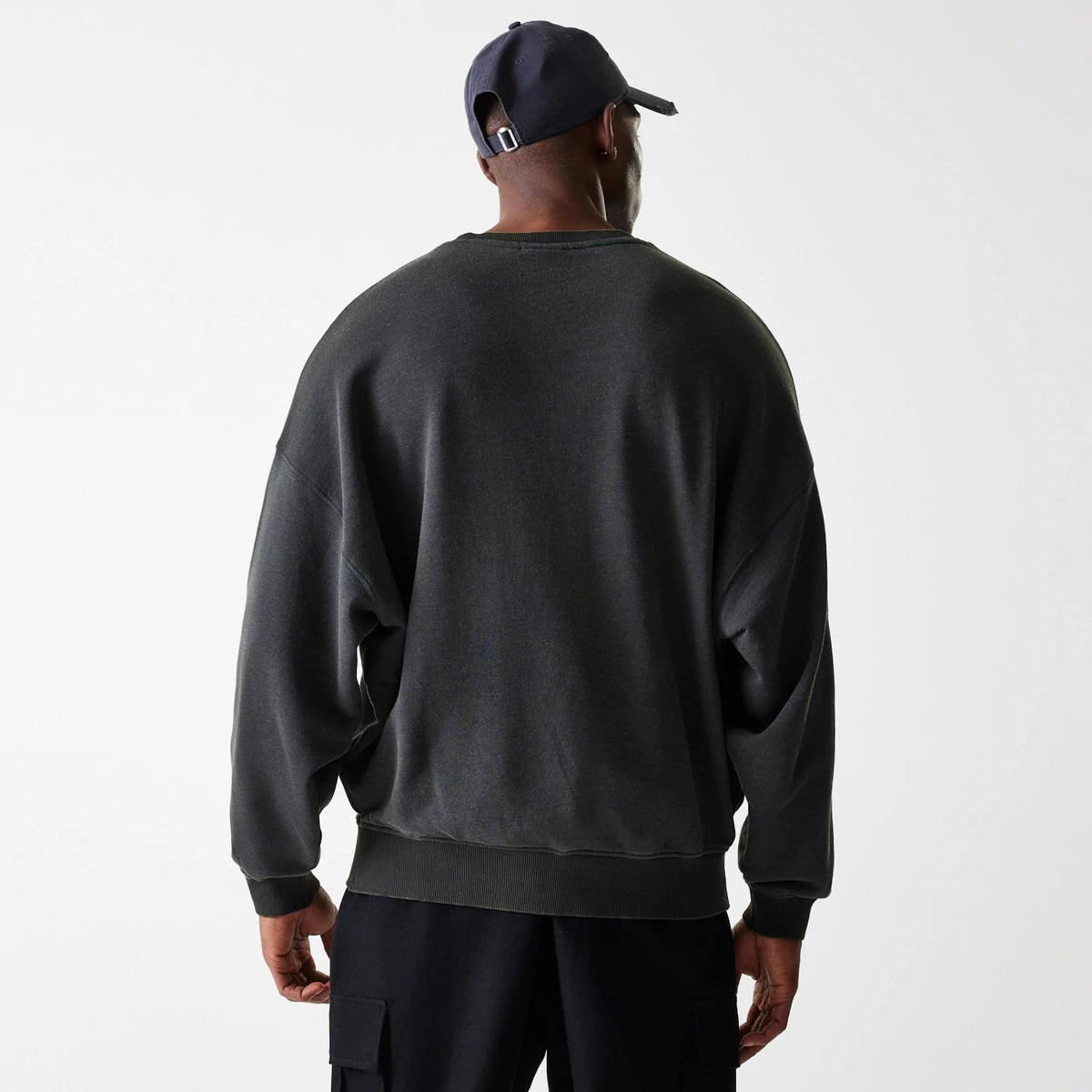 New Era LA Lakers NBA Washed Graphic Grey Oversized Crew Neck Sweater, back view on a model styled with a navy cap, showing the relaxed fit and soft ribbed trims on the cuffs and hem.