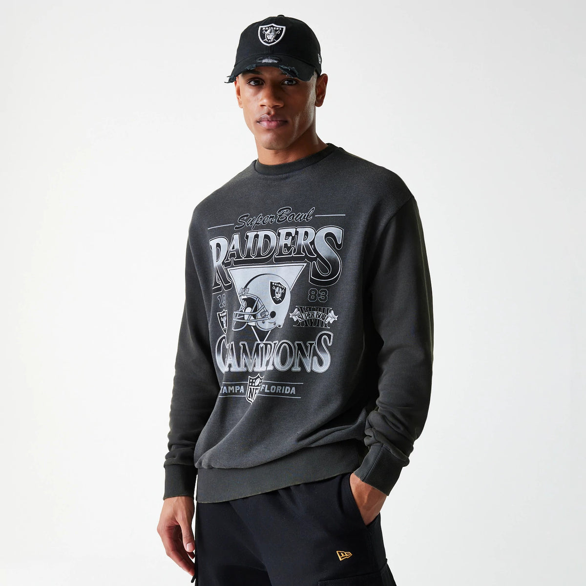 New Era Las Vegas Raiders NFL Washed Super Bowl Grey Oversized Crew Neck Sweater, worn by a model with a cap, showing Super Bowl graphics and Raiders Champions text in white across the chest.