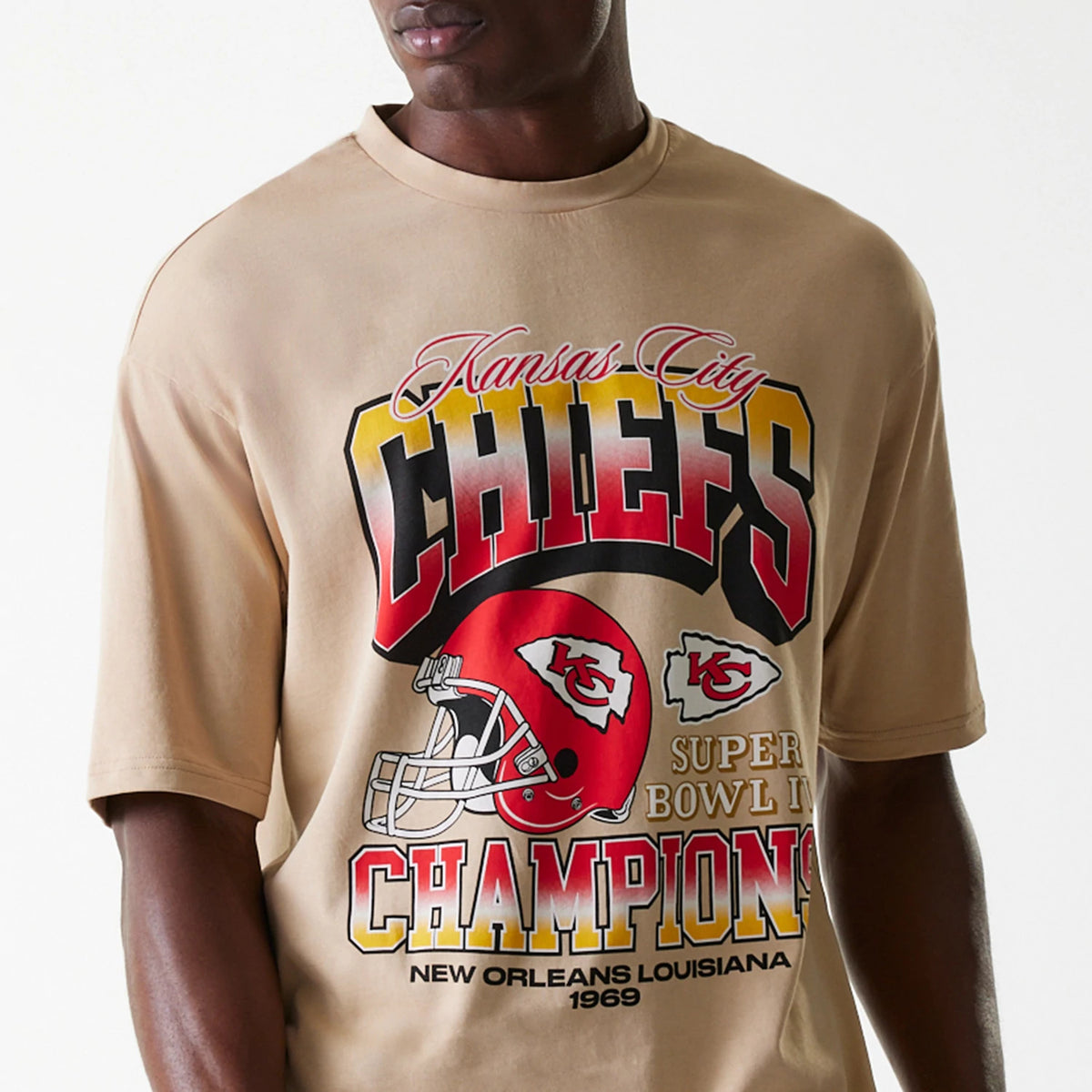 New Era Kansas City Chiefs NFL Washed Super Bowl Beige Oversized T-Shirt, front view showing bold red and yellow Kansas City Chiefs graphics with a football helmet and Super Bowl IV Champions New Orleans Louisiana 1969 text on the beige fabric.