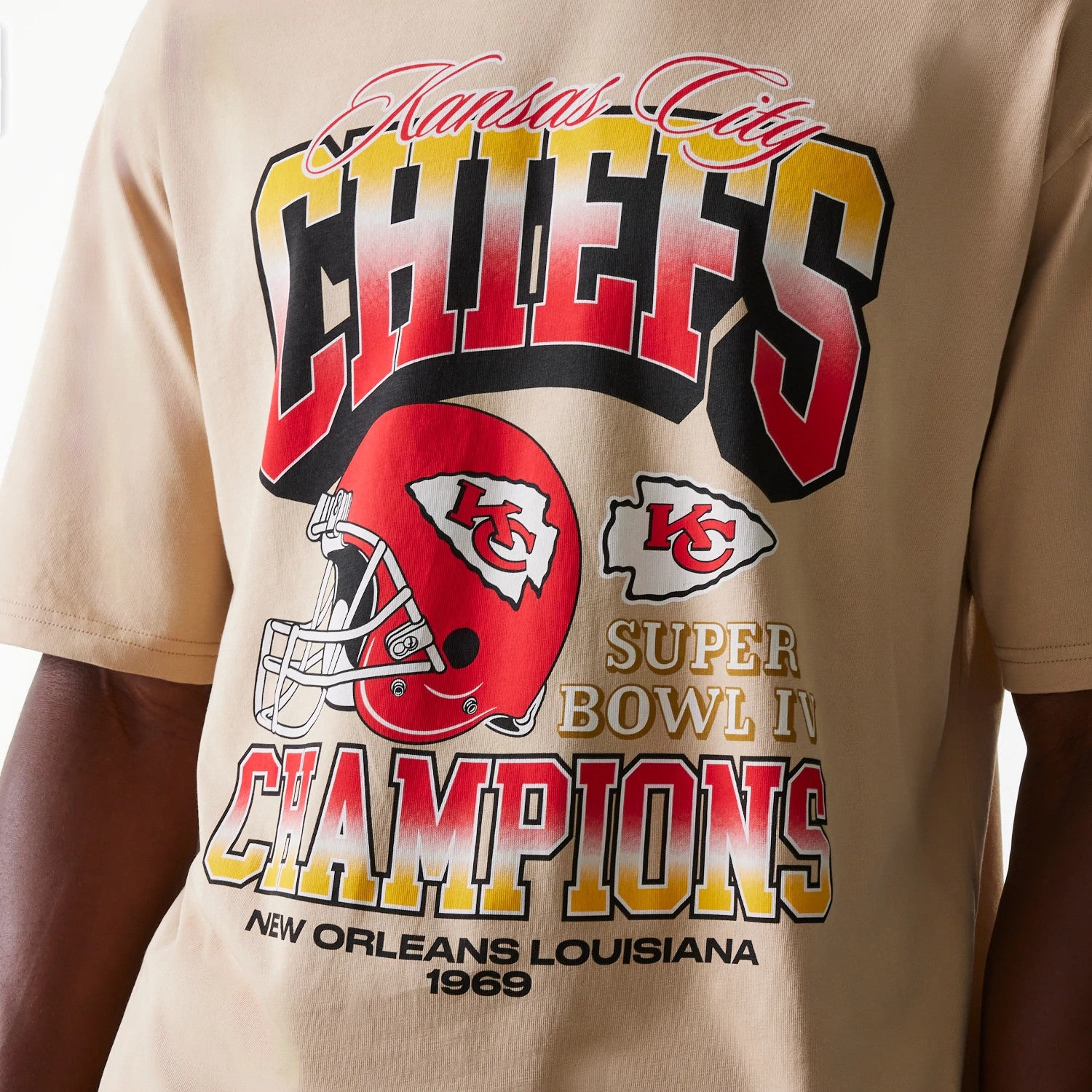 New Era Kansas City Chiefs NFL Washed Super Bowl Beige Oversized T-Shirt, front view showing bold red and yellow CHIEFS text, a red helmet graphic with KC logo, and Super Bowl IV Champions wording with New Orleans Louisiana 1969 below.