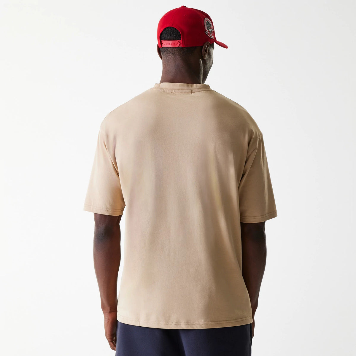 New Era Kansas City Chiefs NFL Washed Super Bowl Beige Oversized T-Shirt, rear view showing the plain beige back of the oversized T-shirt worn by a person, paired with a red cap featuring an embroidered logo.