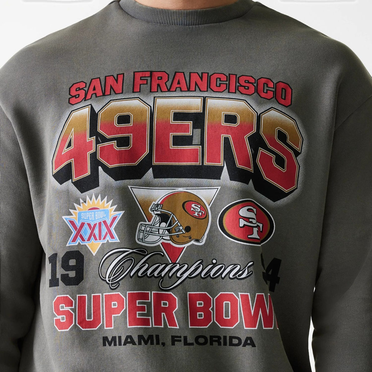 New Era San Francisco 49ers NFL Washed Super Bowl Grey Oversized Crew Neck Sweater, front view on a model showing large 49ERS lettering in red and gold, Super Bowl logos and Champions script across the chest.