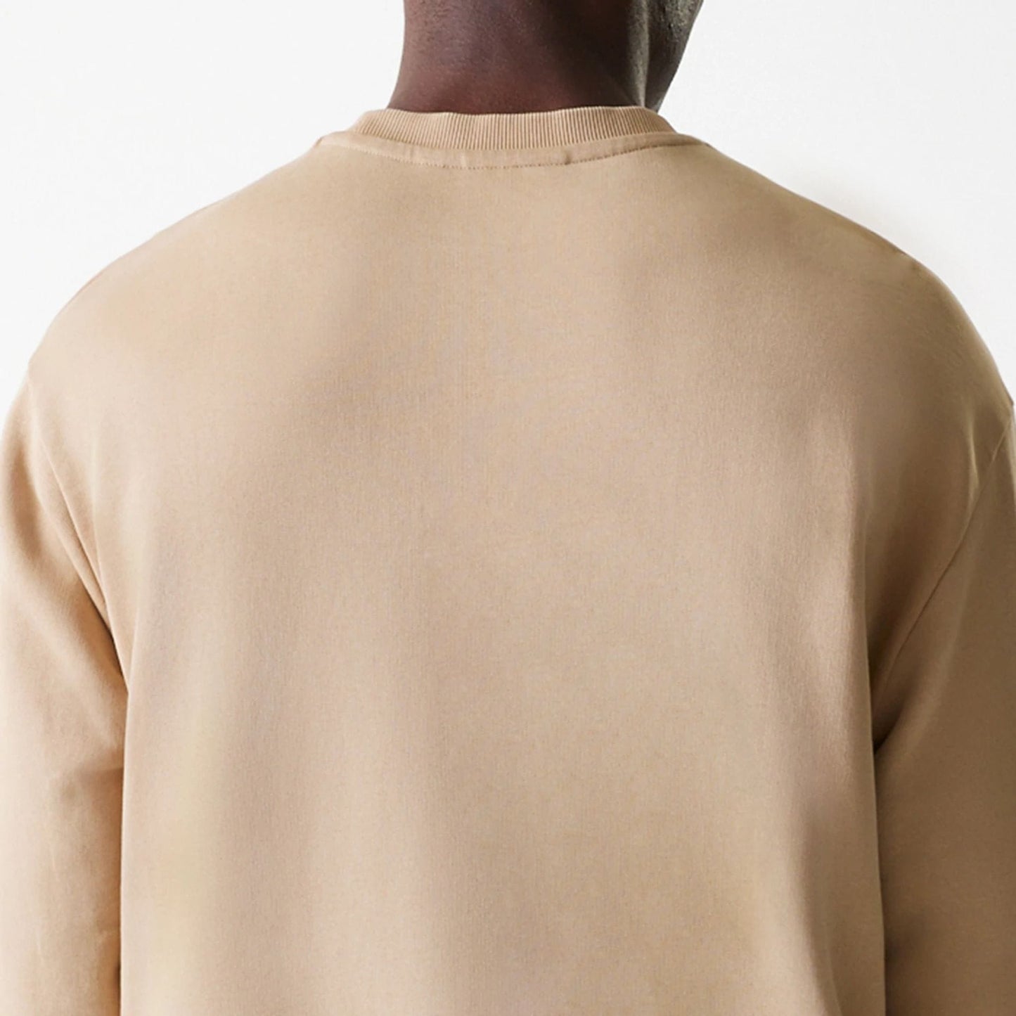 New Era Kansas City Chiefs NFL Washed Super Bowl Beige Oversized Crew Neck Sweater, back view on a model showing the simple ribbed collar and drop shoulders, highlighting the relaxed fit and soft beige fabric.