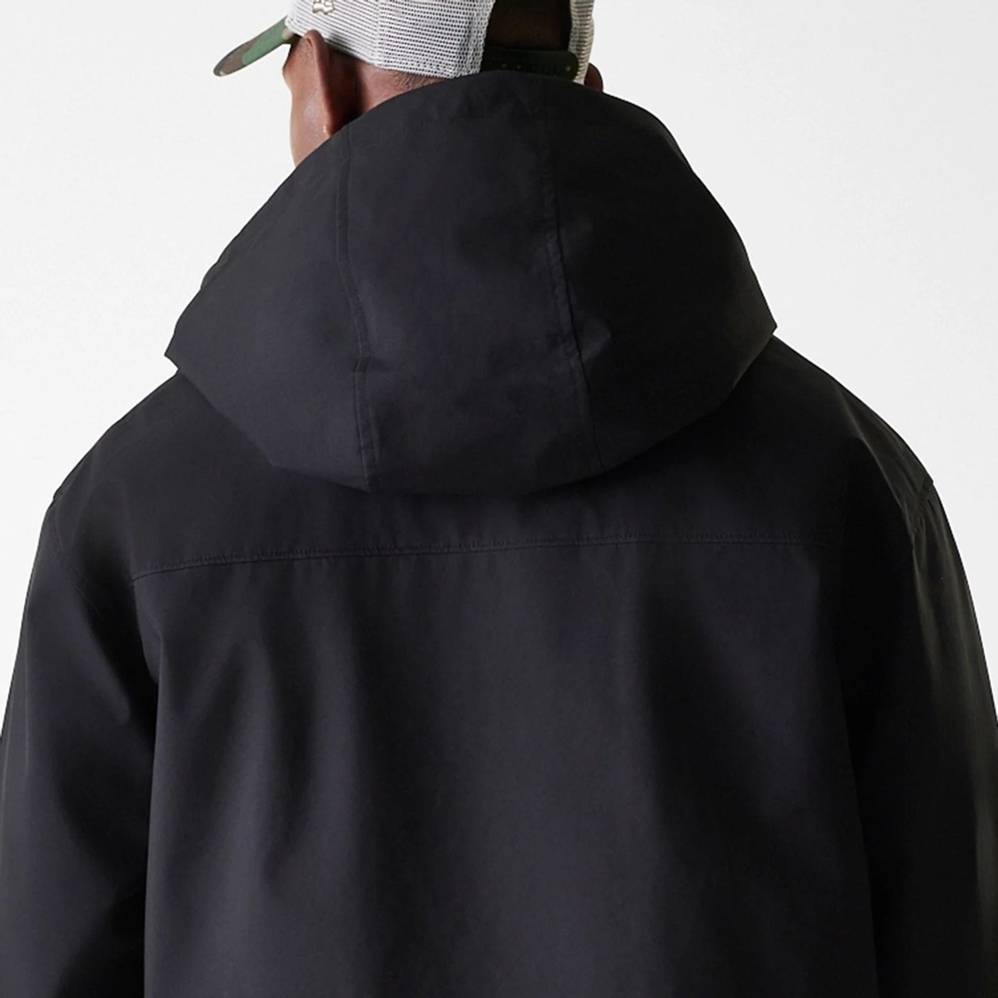 New Era Black Coach Jacket, rear view showing the black hooded design from the back with a seam running horizontally across the shoulder blades and a curved black hemline at the bottom.