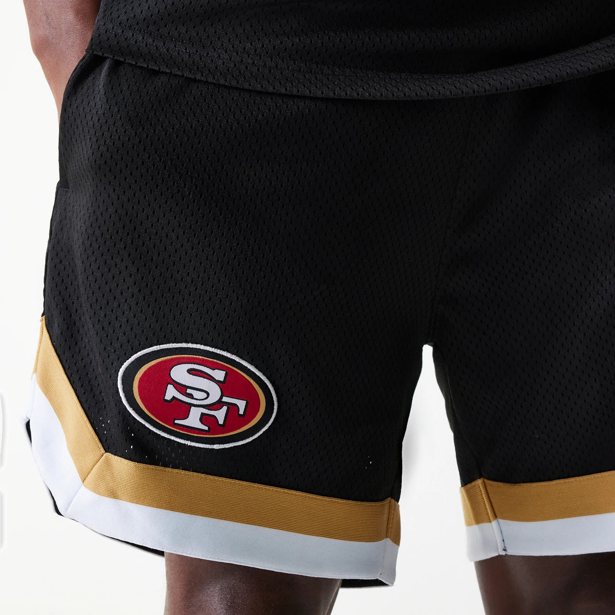 New Era San Francisco 49ers NFL Mesh Black Shorts, front view showing the black mesh fabric with a raised team logo on the lower left leg, accented by gold and white striping along the hem.