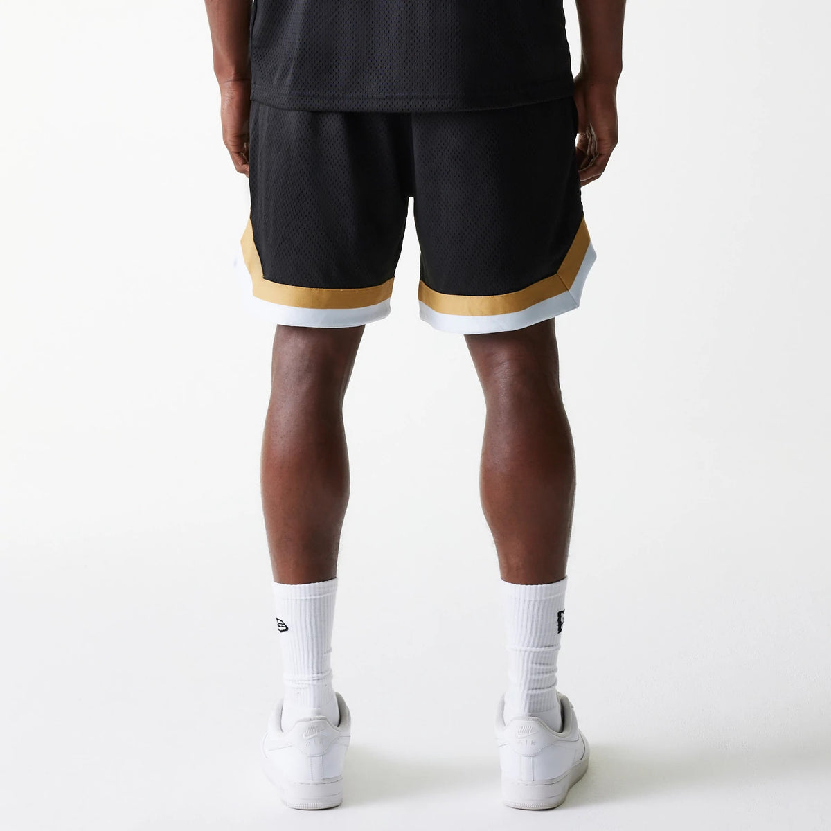 New Era San Francisco 49ers NFL Mesh Black Shorts, rear view showing the black mesh fabric with a gold stripe near the hem and a white band below it, worn by a model with hands resting by the sides.