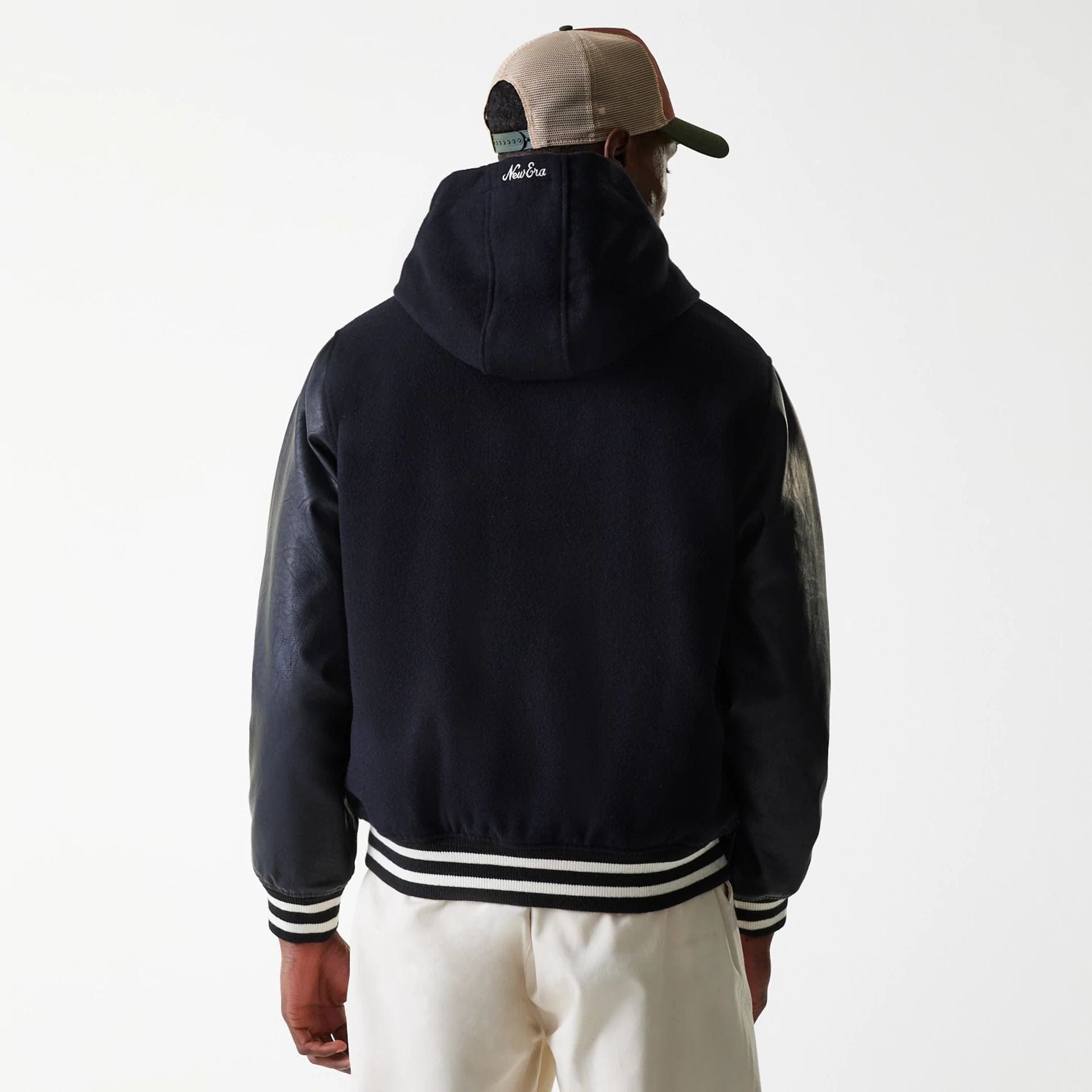 The Male model is wearing New Era Black Hooded Varsity Jacket 2
