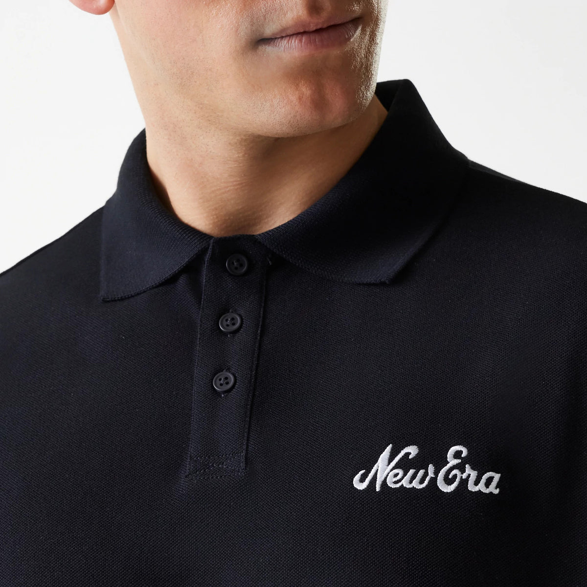 New Era Script Black Polo T-Shirt, three-quarter view showing the collared neckline with black buttons down the placket, and the white embroidered New Era script logo on the left chest.