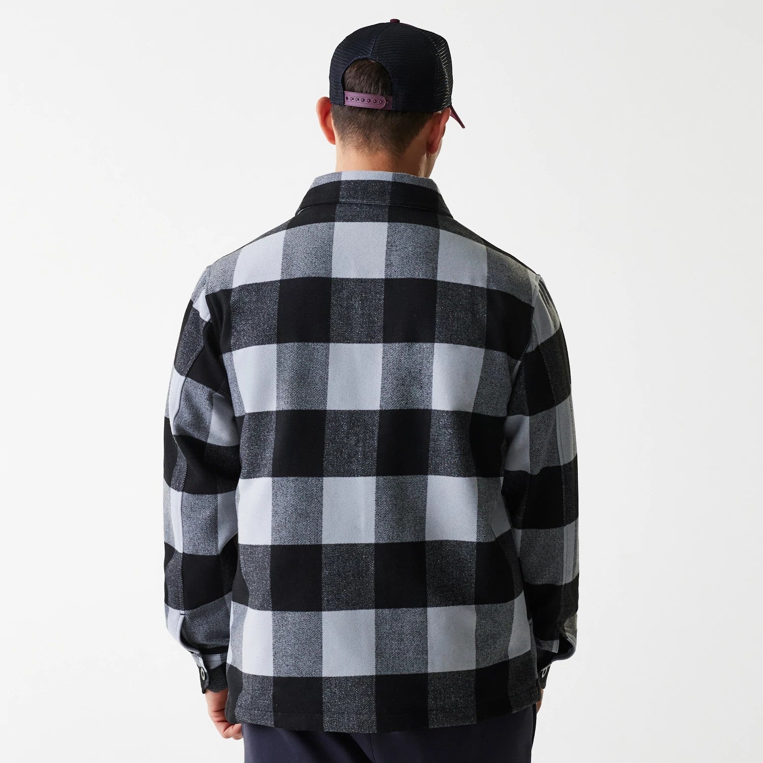 New Era Black Shacket, back view on a model wearing a black and purple snapback cap, showcasing the large black and grey check pattern across the back with buttoned cuffs on the sleeves.