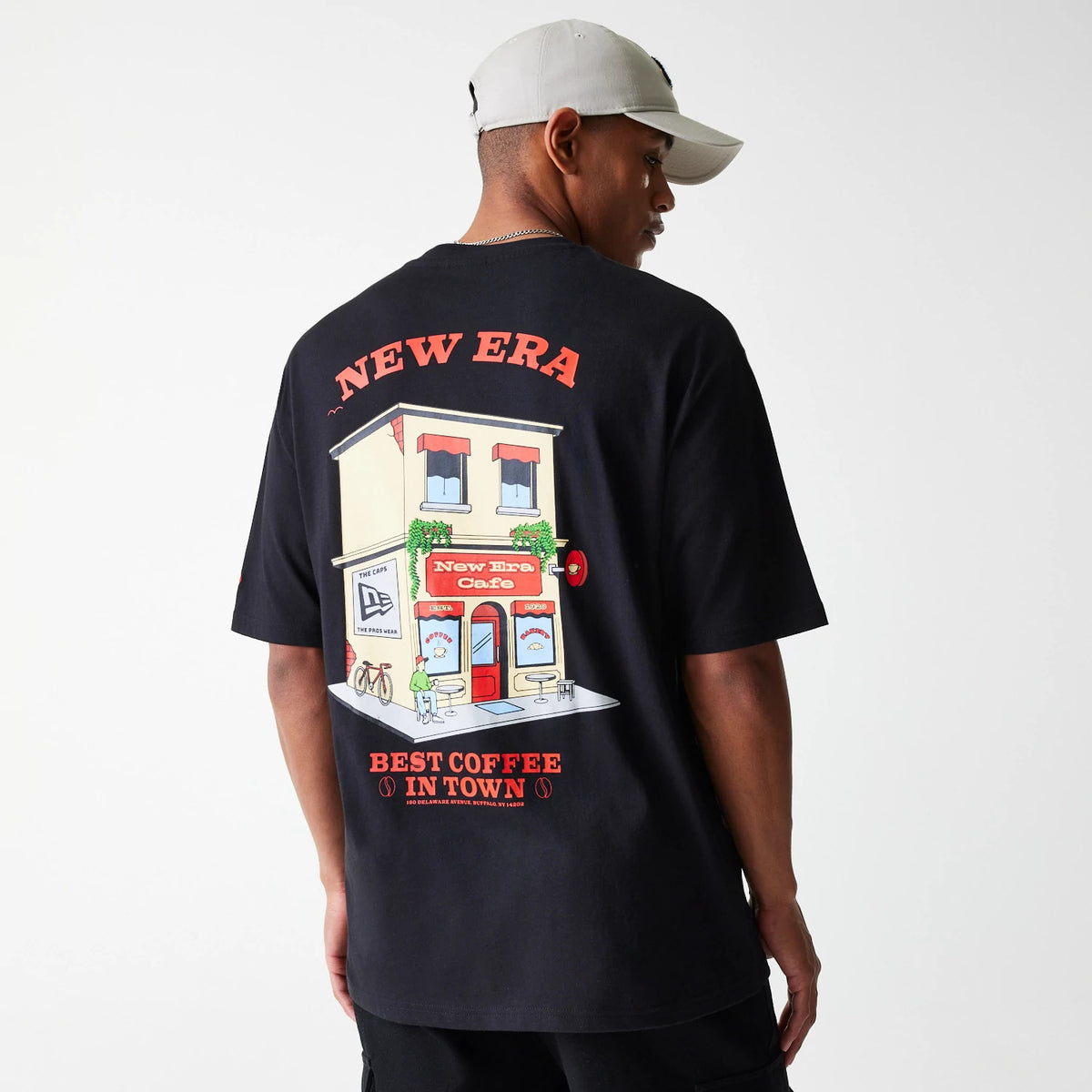 New Era Cafe Graphic Black Oversized T-Shirt, rear view showing a colourful illustrated café graphic with New Era in bold red letters above and Best Coffee in Town below on the black fabric.