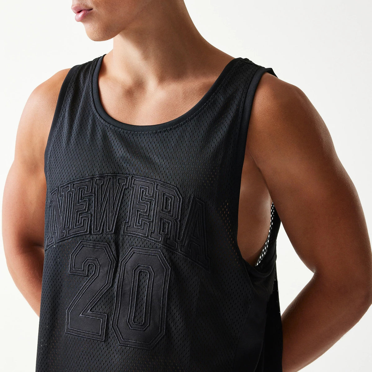 New Era Mesh Black Mesh Vest, three-quarter view on a model showing raised embroidered NEWERA lettering and the number 20 on the black mesh fabric, highlighting the sleeveless design and relaxed fit.