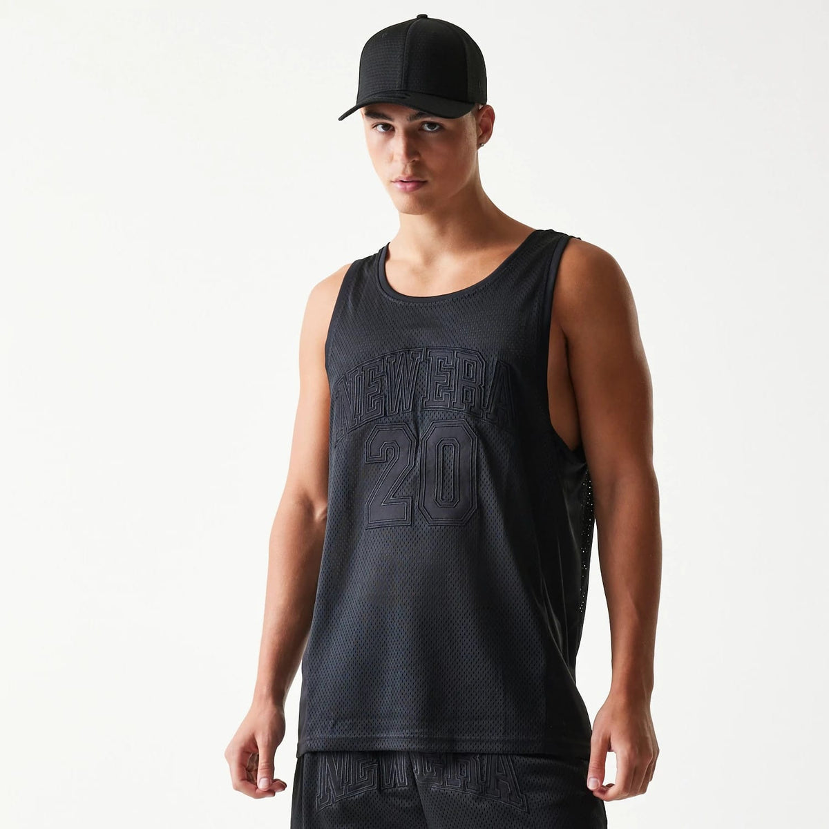 New Era Mesh Black Mesh Vest, front view on a model styled with a matching black cap, featuring NEW ERA and the number 20 embroidered across the chest on a breathable mesh fabric.
