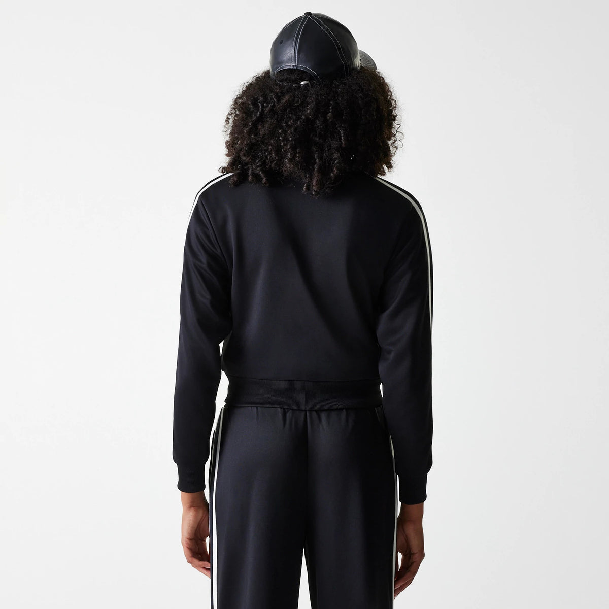 New Era New York Yankees Womens MLB Midi Logo Black Track Jacket, rear view showing the black track jacket with white stripes along the sleeves worn by a model, paired with matching black trousers and a black cap.