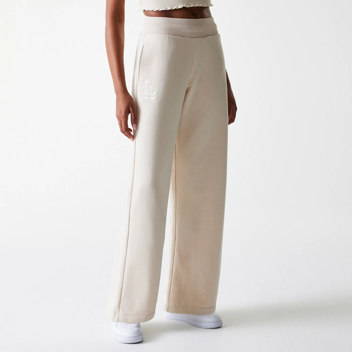 New Era LA Dodgers Womens MLB Tonal Light Beige Straight Leg Joggers, front view on a model with white trainers and a textured crop top, showing the white embroidered LA logo on the left thigh and ribbed waistband detailing.