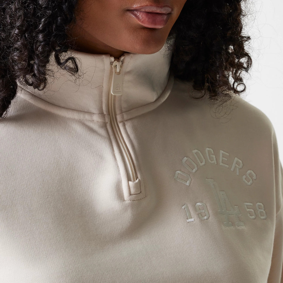 New Era LA Dodgers Womens MLB Tonal Light Beige Cropped 1/4 Zip Sweater, front view on a model showing the raised embroidered Dodgers lettering and LA logo with the year 1958, highlighting the high collar and zip closure.