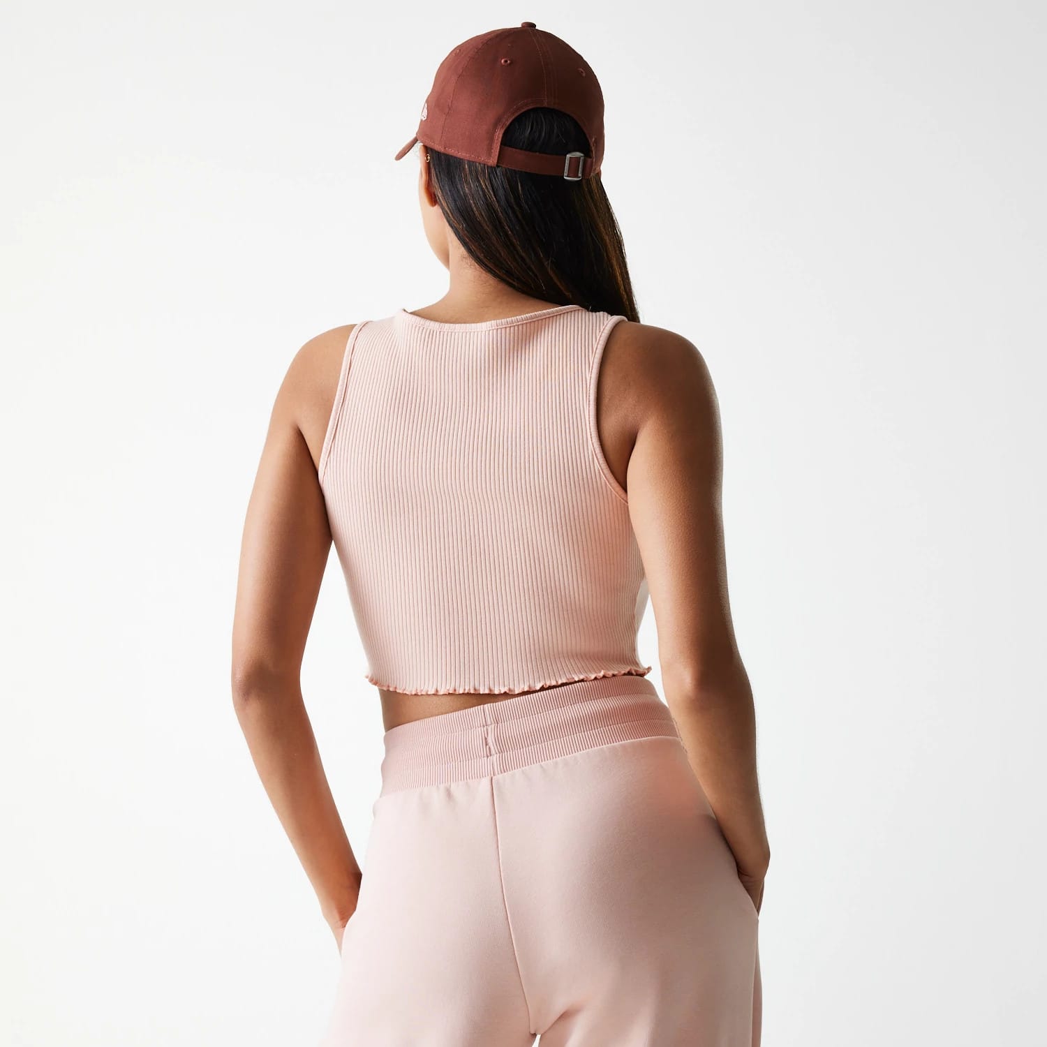 New Era New York Yankees Womens MLB Rib Pastel Pink Rib Tank Top, back view on a model with long hair, styled with pink ribbed fabric and cropped hem, paired with matching light pink trousers and a brown cap.