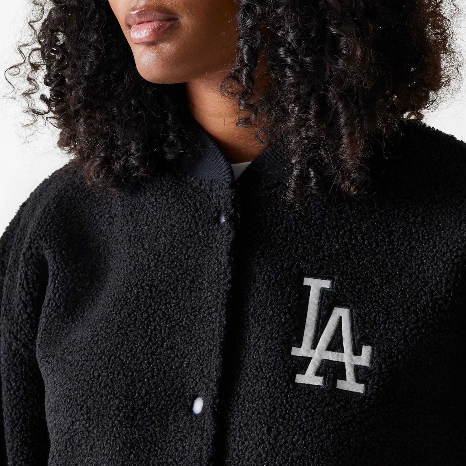 New Era LA Dodgers Womens MLB Black Oversized Sherpa Bomber Jacket, front view showing the black textured fabric with a white raised LA logo on the left chest, black ribbed collar, and several buttons running down the front.