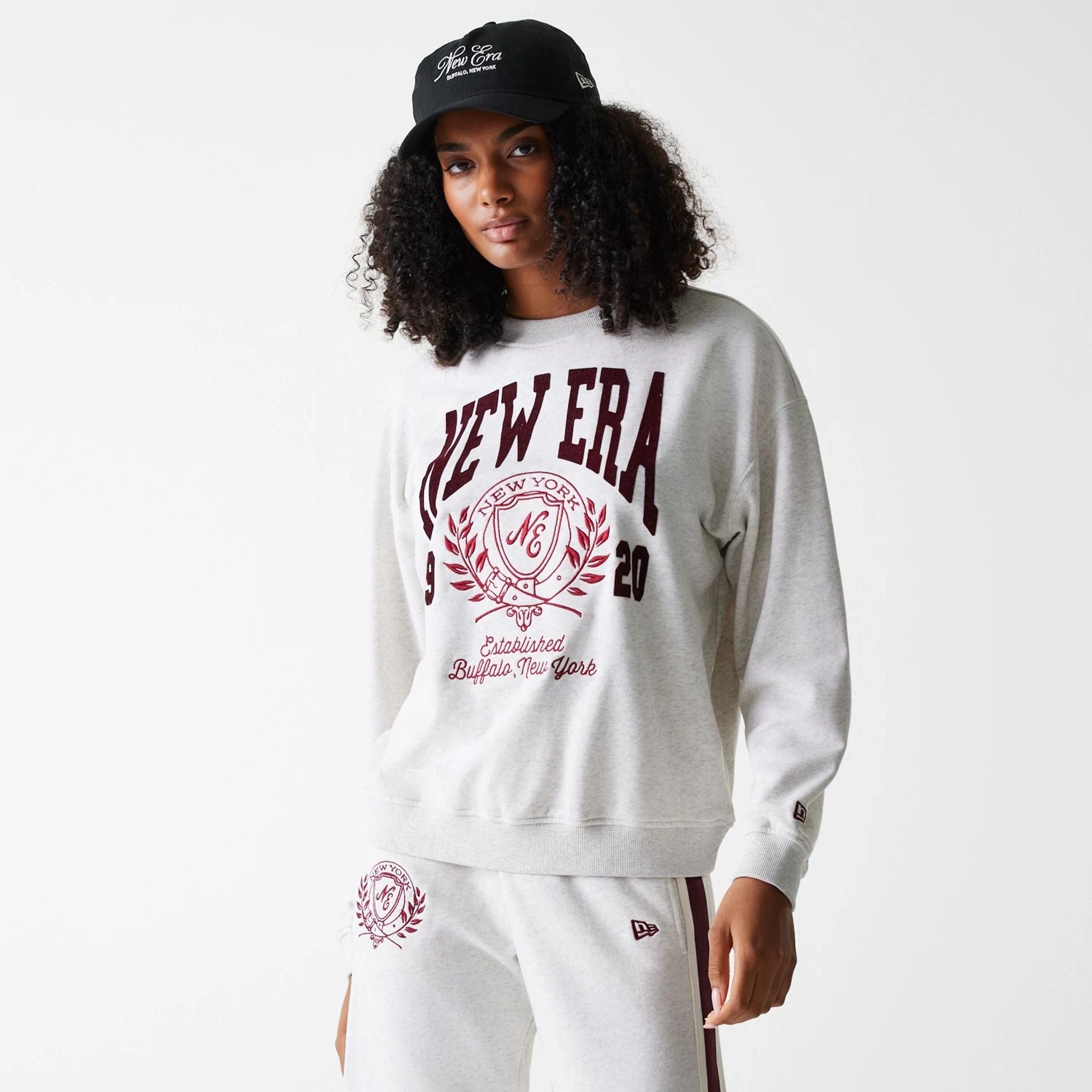 The Female model is wearing Womens New Era Crest Graphic Pastel Grey Crew Neck Sweater 1
