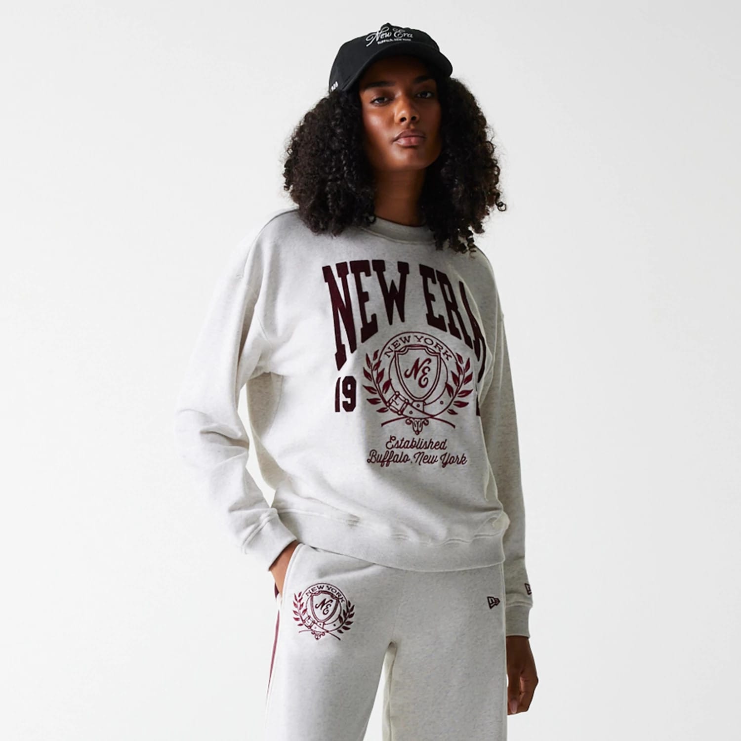 The Female model is wearing Womens New Era Crest Graphic Pastel Grey Crew Neck Sweater 4