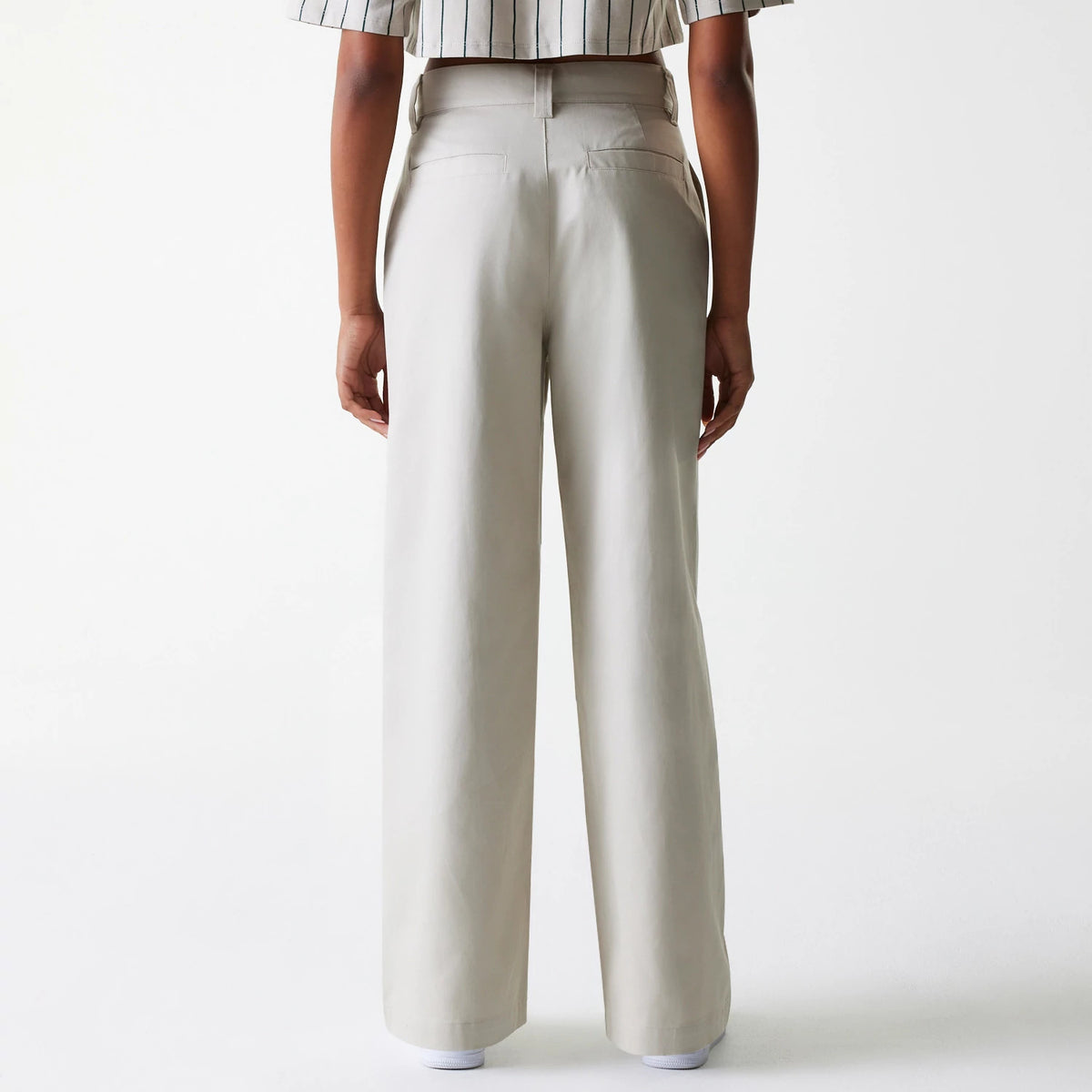 Womens New Era Light Beige Wide Leg Chino Trousers, rear view on a model showing high waist design and two back pockets, paired with a striped short-sleeve top for a casual and modern look.