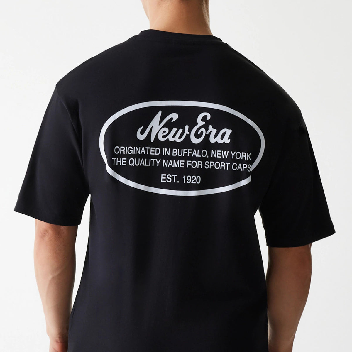 New Era Trucker Patch Black Oversized T-Shirt, back view showing the oversized black shirt with a large white print featuring the New Era logo and text framed within an oval on the upper back.