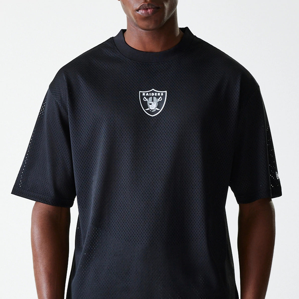 New Era Las Vegas Raiders NFL Essentials Black Oversized Mesh T-Shirt, front view showing the black mesh fabric with a central white Raiders logo on the chest and a raised New Era logo on the left sleeve.