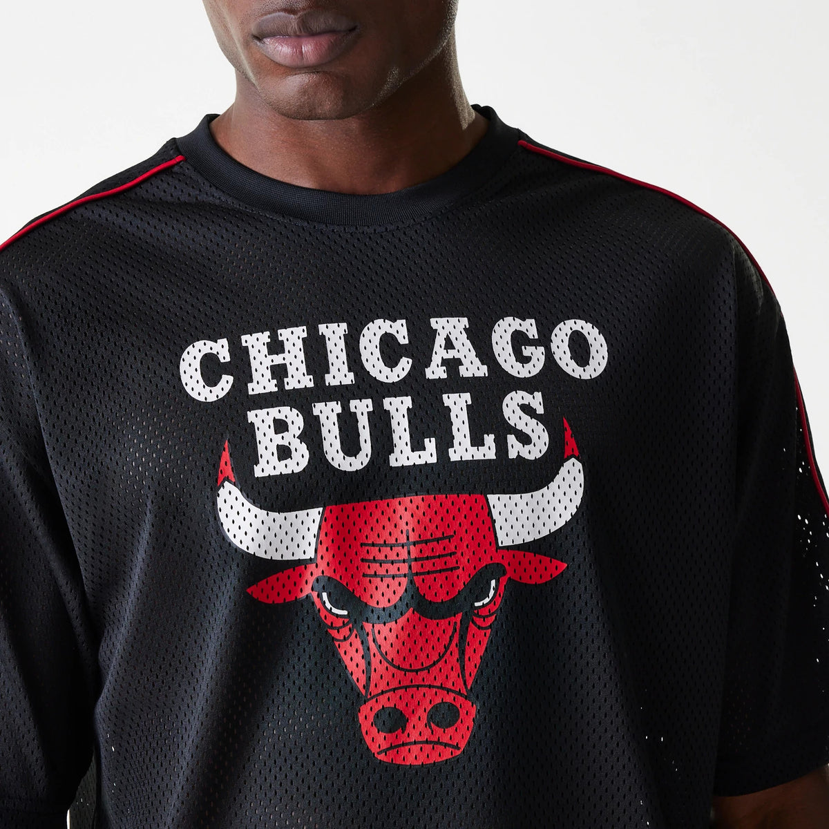New Era Chicago Bulls NBA Piping Black Oversized Mesh T-Shirt, front view showing a bold white Chicago Bulls print above the fierce red bull logo on the black mesh fabric, with red piping details on the shoulders.