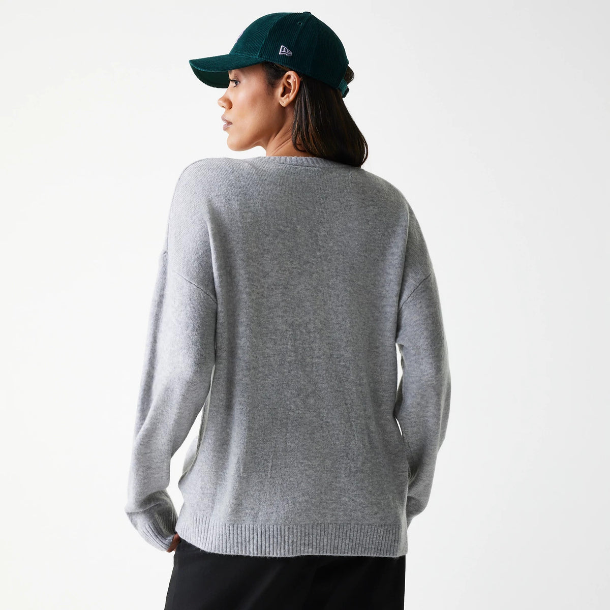 New Era LA Dodgers Womens MLB Knit Grey Crew Neck Sweater, back view on a model wearing a dark green cap with the New Era flag logo on the left side, showing the plain light grey sweater with ribbed cuffs and hem.